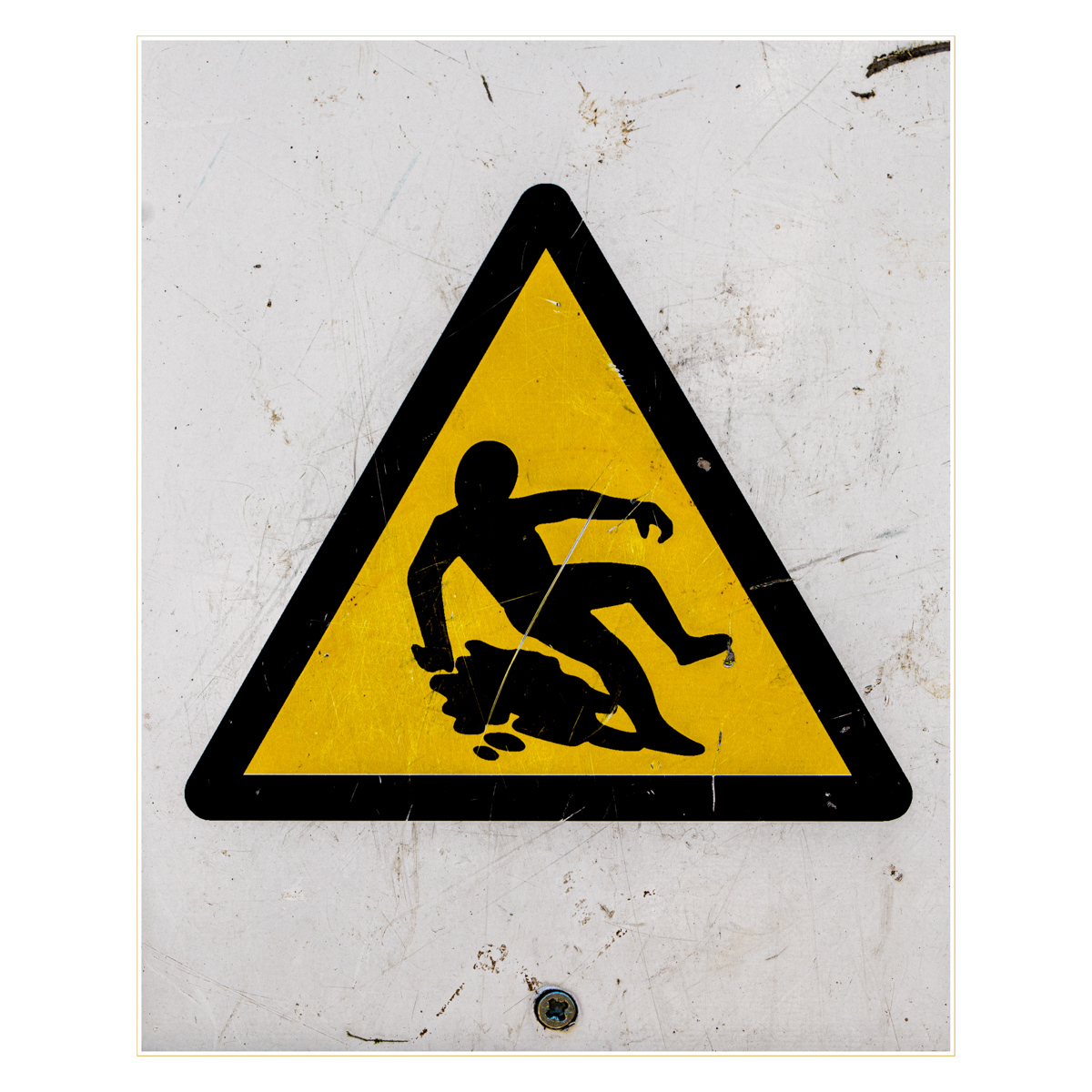 A warning sign, which is a yellow triangle containing a drawing of a cartoon man slipping on something.